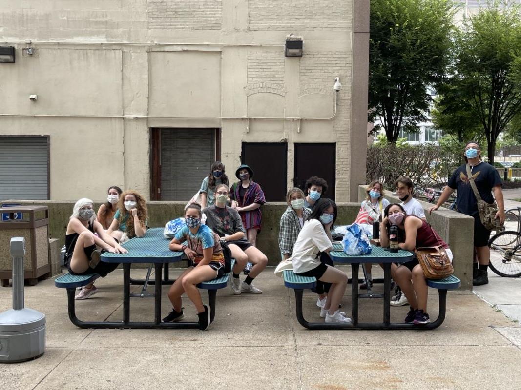 学生们戴着口罩坐在宿舍楼前的户外桌子旁